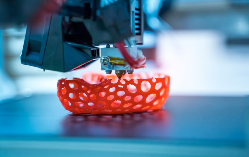 3D printer creating a detailed red object on a manufacturing platform