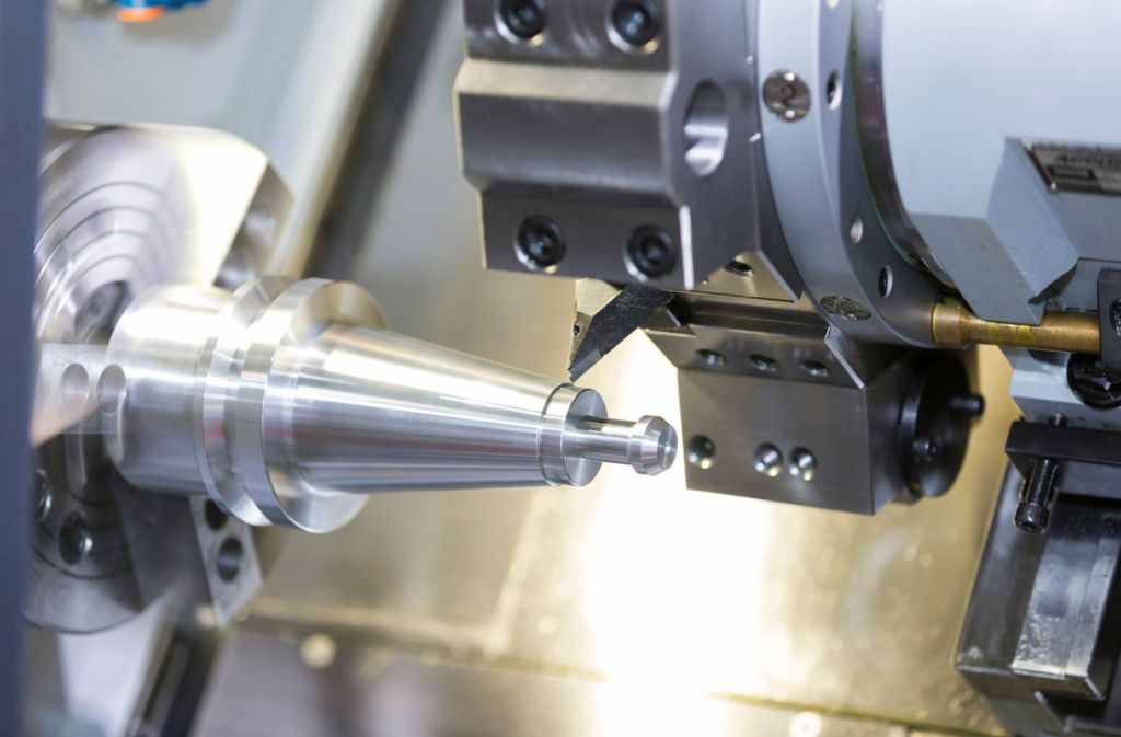 Close-up of CNC machine cutting a white metal piece.