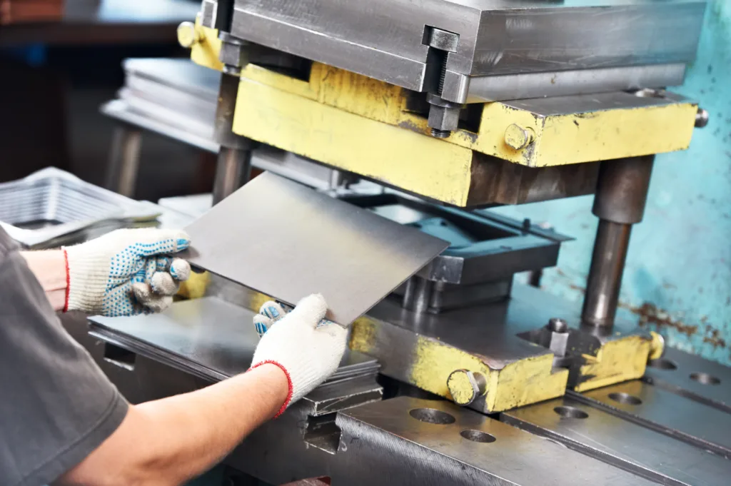 Worker operates a machine for bending sheet metal