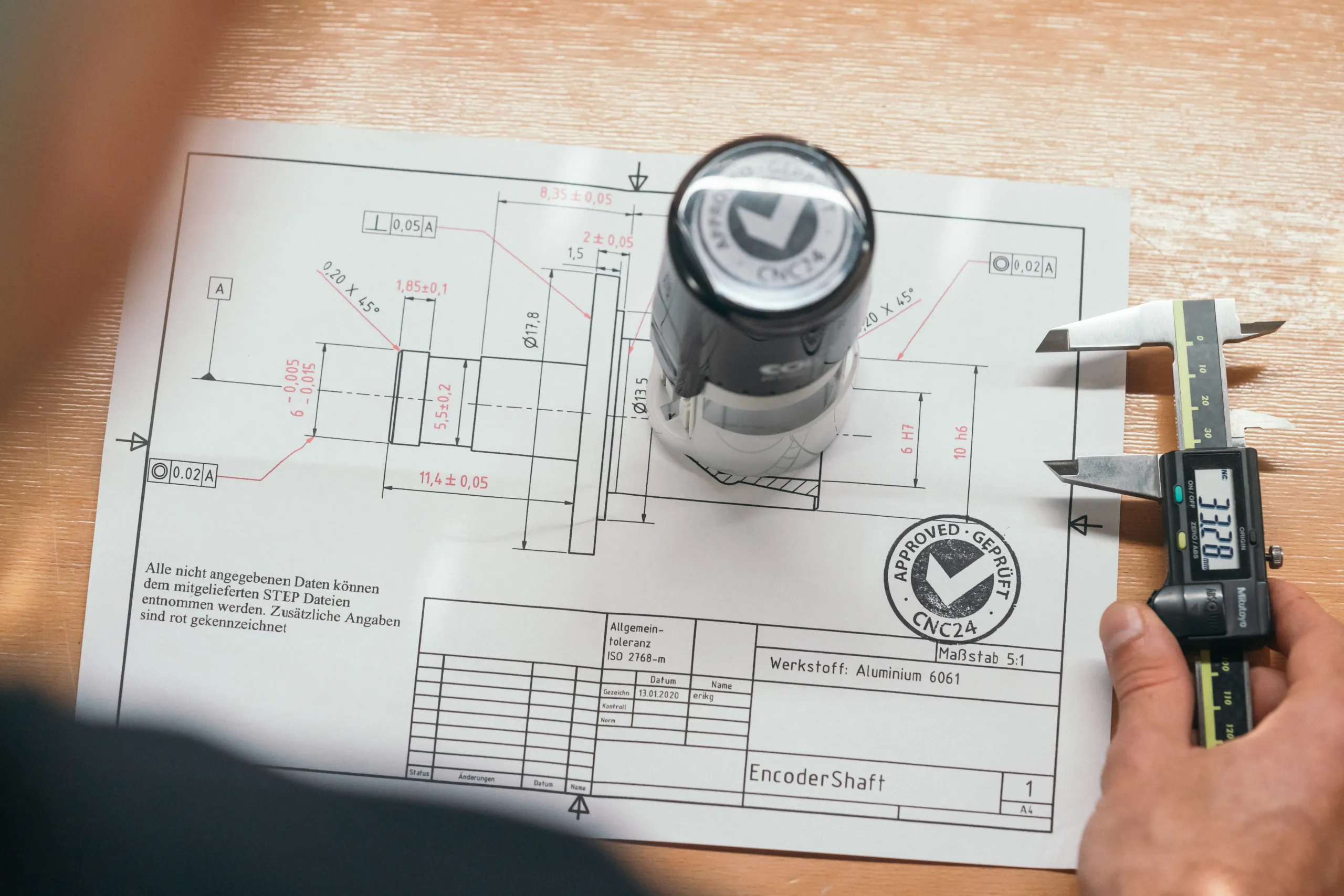 "Meetproces van een CNC24-medewerker met een digitale schuifmaat en technische plannen"